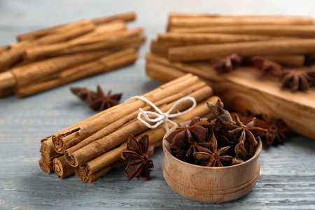 Aromatic cinnamon sticks and anise on gray wooden table, closeup