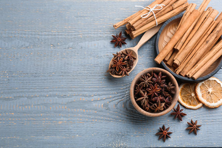 Aromatic cinnamon sticks and anise on gray wooden table, flat lay. Space for text
