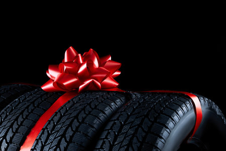 Winter tires with red ribbon on black background, closeupの写真素材