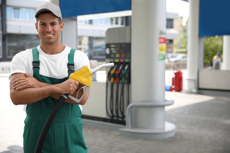 Worker with fuel pump nozzle at modern gas stationの写真素材