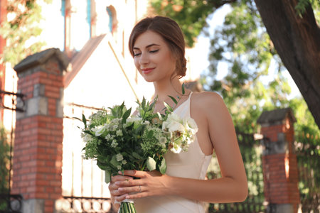 Gorgeous bride in beautiful wedding dress with bouquet near churchの写真素材