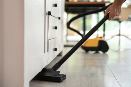Young man using vacuum cleaner at home, closeupの写真素材