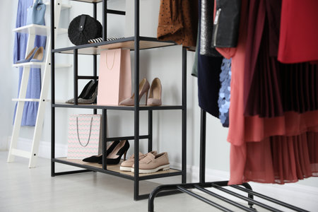 Different stylish shoes and bags on shelving unit in dressing roomの写真素材