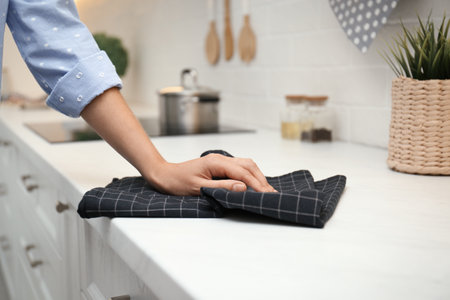 Woman wiping white table with kitchen towel, closeupの写真素材