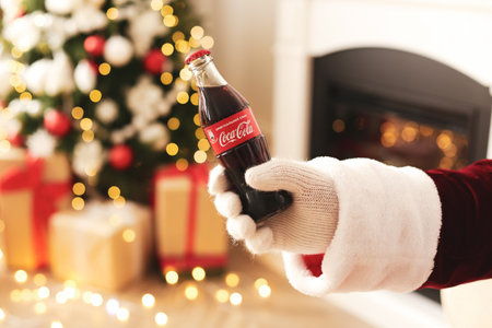 MYKOLAIV, UKRAINE - JANUARY 18, 2021: Santa Claus holding Coca-Cola bottle in room decorated for Christmas, closeupのeditorial素材