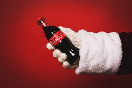 MYKOLAIV, UKRAINE - JANUARY 18, 2021: Santa Claus holding Coca-Cola bottle in hand on red...