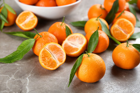 Fresh tangerines with green leaves on gray tableの写真素材