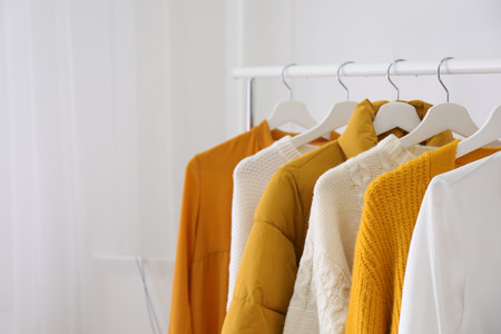 Rack with stylish warm clothes indoors, closeup. Space for textの写真素材