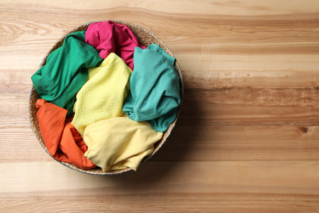 Wicker basket with laundry on wooden surface, top view. Space for textの写真素材