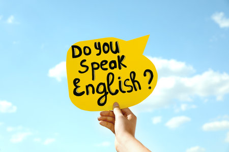 Woman holding paper speech bubble with question Do You Speak English against blue sky, closeupの写真素材