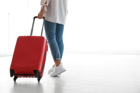 Woman with red travel suitcase in airport. Space for textの写真素材
