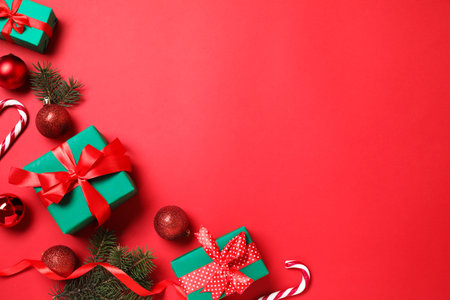 Gift boxes and Christmas decorations on red background, flat lay. Space for textの写真素材