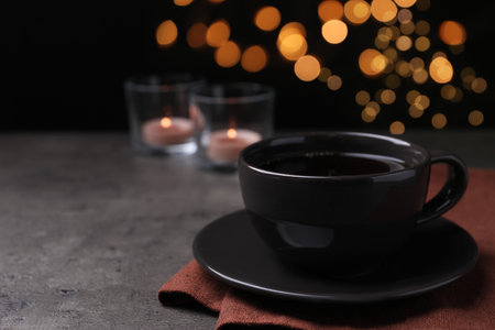 Cup of hot coffee on dark table against black background, space for textの写真素材