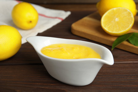 Delicious lemon curd in sauce boat on wooden tableの写真素材