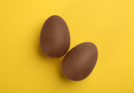Sweet chocolate eggs on yellow background, flat layの写真素材