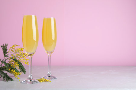 Glasses of Mimosa cocktail on light table. Space for textの写真素材