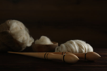 Soft white wool and spindles on wooden table, closeupの写真素材