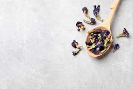Spoon and dry organic blue Anchan on light gray table, flat lay with space for text. herbal tea