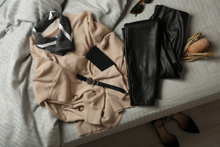 Stylish look with cashmere sweater, flat lay. Women's clothes and accessories on bedの写真素材