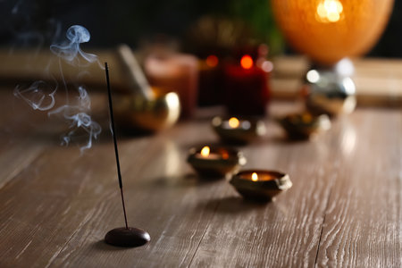 Incense stick smoldering on wooden table in room. Space for textの写真素材
