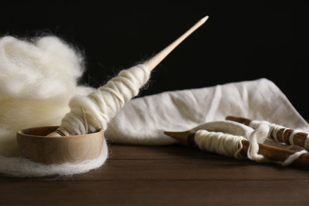 Spindles and soft white wool on wooden tableの写真素材