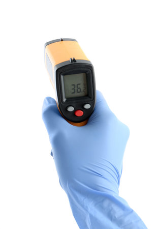 Doctor with infrared thermometer on white background, closeup. Checking temperature during Covid-19...