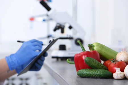 Fresh vegetables on table, scientist proceeding quality control in laboratoryの写真素材