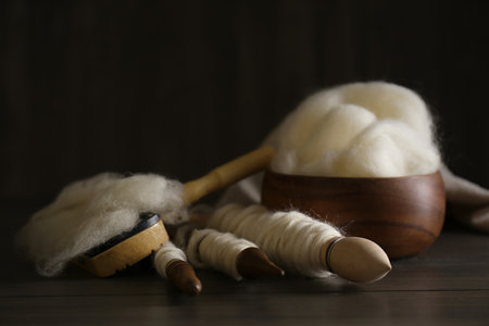 Soft white wool and spindles on wooden table, closeupの写真素材