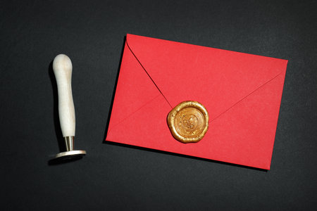 Envelope with wax seal and stamp on black background, flat layの写真素材