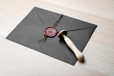 Envelope with wax seal and stamp on white wooden tableの写真素材