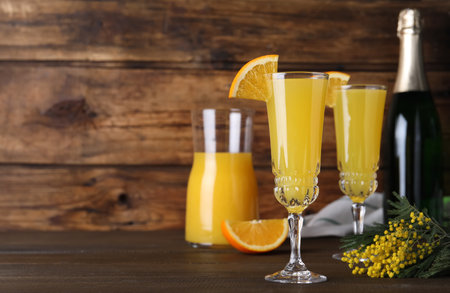 Glasses of Mimosa cocktail with garnish on wooden table. Space for textの写真素材