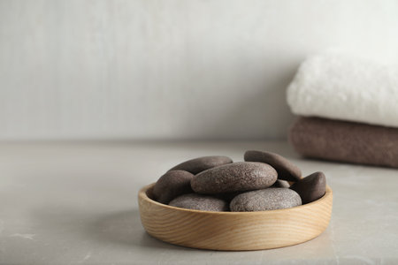 Spa stones in wooden tray on light tableの写真素材