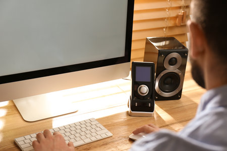 Man working on computer at wooden table indoors, closeup. audio speaker systemの写真素材