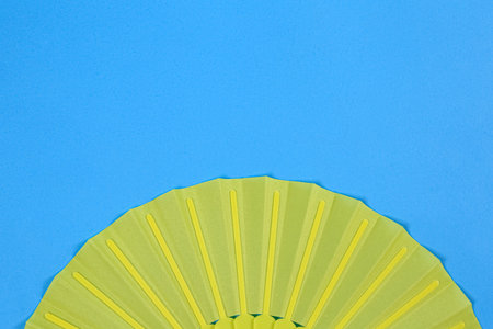 Yellow hand fan on light blue background, top view. Space for textの写真素材