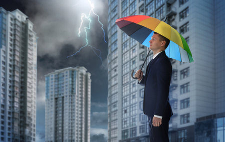 Businessman with umbrella in city center. insurance conceptの写真素材