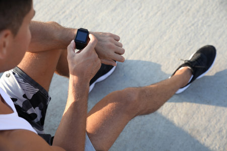 Man checking fitness tracker after training outdoors, closeupの写真素材