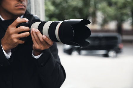 Private detective with modern camera spying outdoors, focus on lensの写真素材