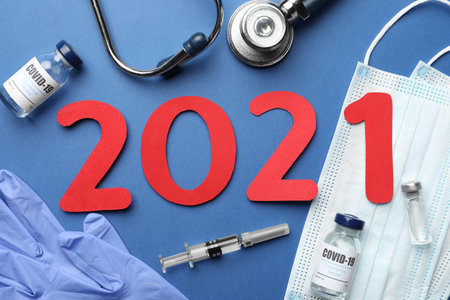Flat lay composition with coronavirus vaccine and number 2021 on blue backgroundの写真素材