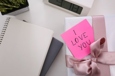 Memory sticker with phrase I Love You on gift box at table, flat lay. Valentine's Day celebrationの写真素材
