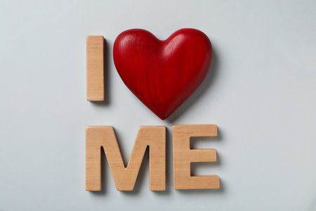 Phrase I Love Me made of wooden letters and red heart on light background, flat layの写真素材