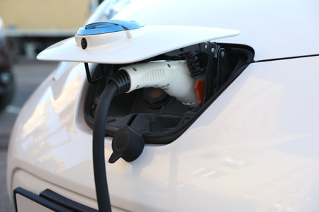 Charging modern electric car from station outdoors, closeup