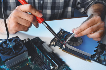 Technician repairing electronic circuit board with soldering iron at table, closeupの写真素材