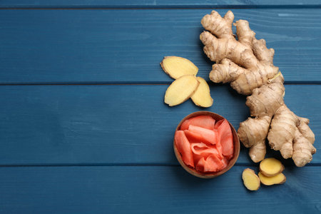 Spicy pickled ginger and root on blue wooden table, flat lay. Space for textの写真素材