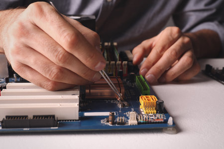Technician repairing electronic circuit board at table, closeupの写真素材