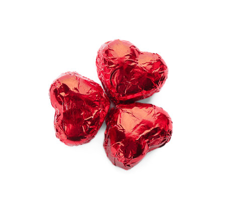 Heart shaped chocolate candies in red foil on white background, top viewの写真素材
