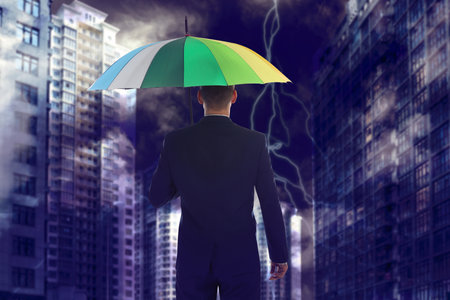 Businessman with umbrella in city center. insurance conceptの写真素材