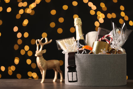 Basket with Christmas gift set on wooden table against blurred festive lightsの写真素材