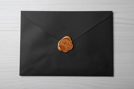 Black envelope with wax seal on white wooden background, top viewの写真素材