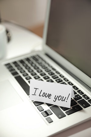 Note with handwritten text I Love You on laptop. romantic message