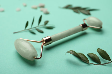 natural face roller and leaves on turquoise backgroundの写真素材